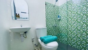 Un baño con un lavamanos blanco, un inodoro y una ducha con mosaicos verdes.