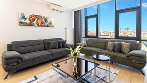 Una sala de estar moderna con dos sofás, una mesa de centro y un amplio ventanal con vista a la ciudad.