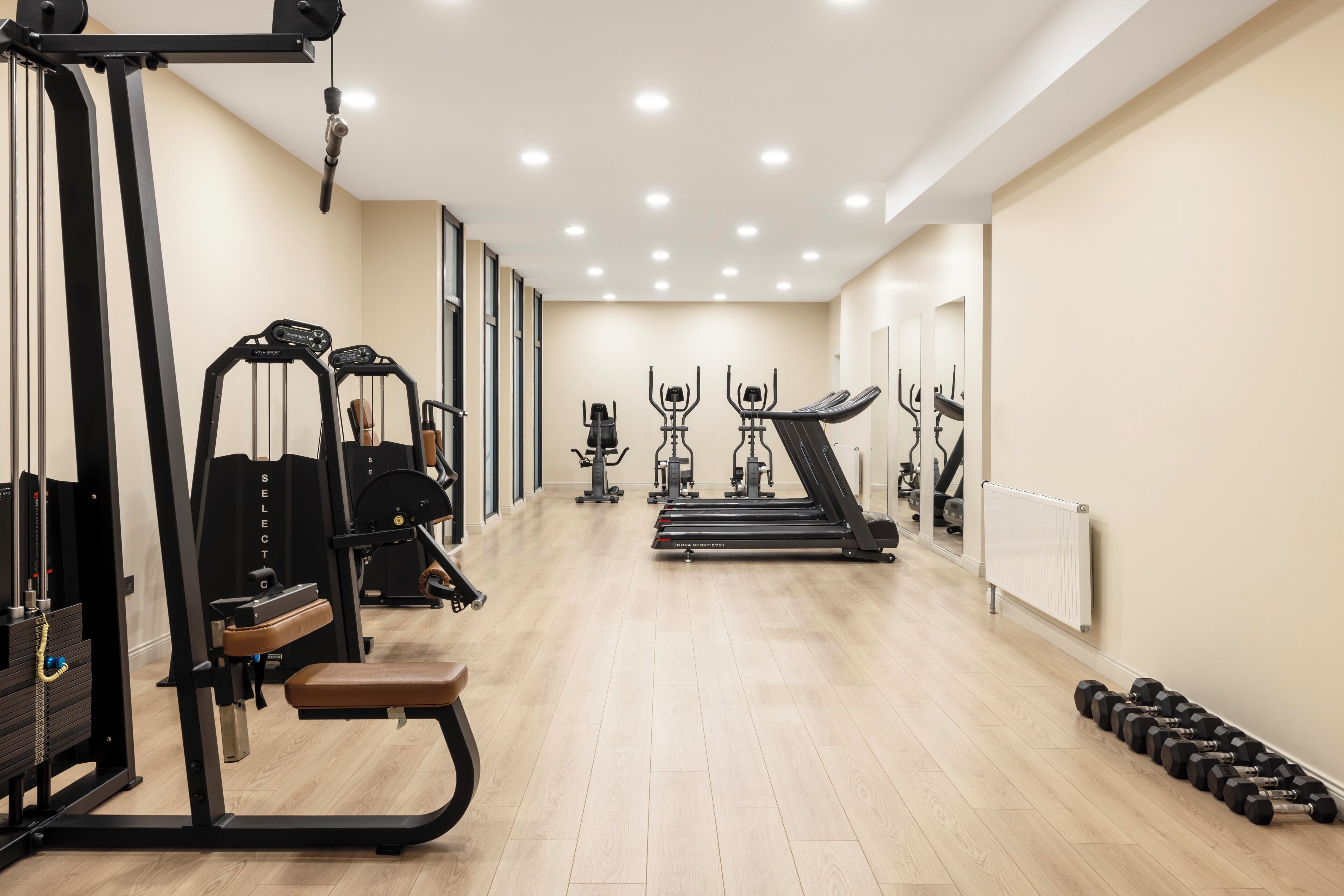 A gym with cardio machines, weightlifting equipment, and dumbbells.