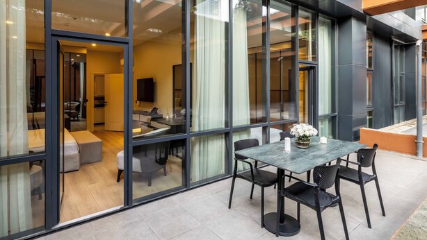 Un interior moderno con una pared de vidrio, un comedor con mesa y sillas, y un sofá.
