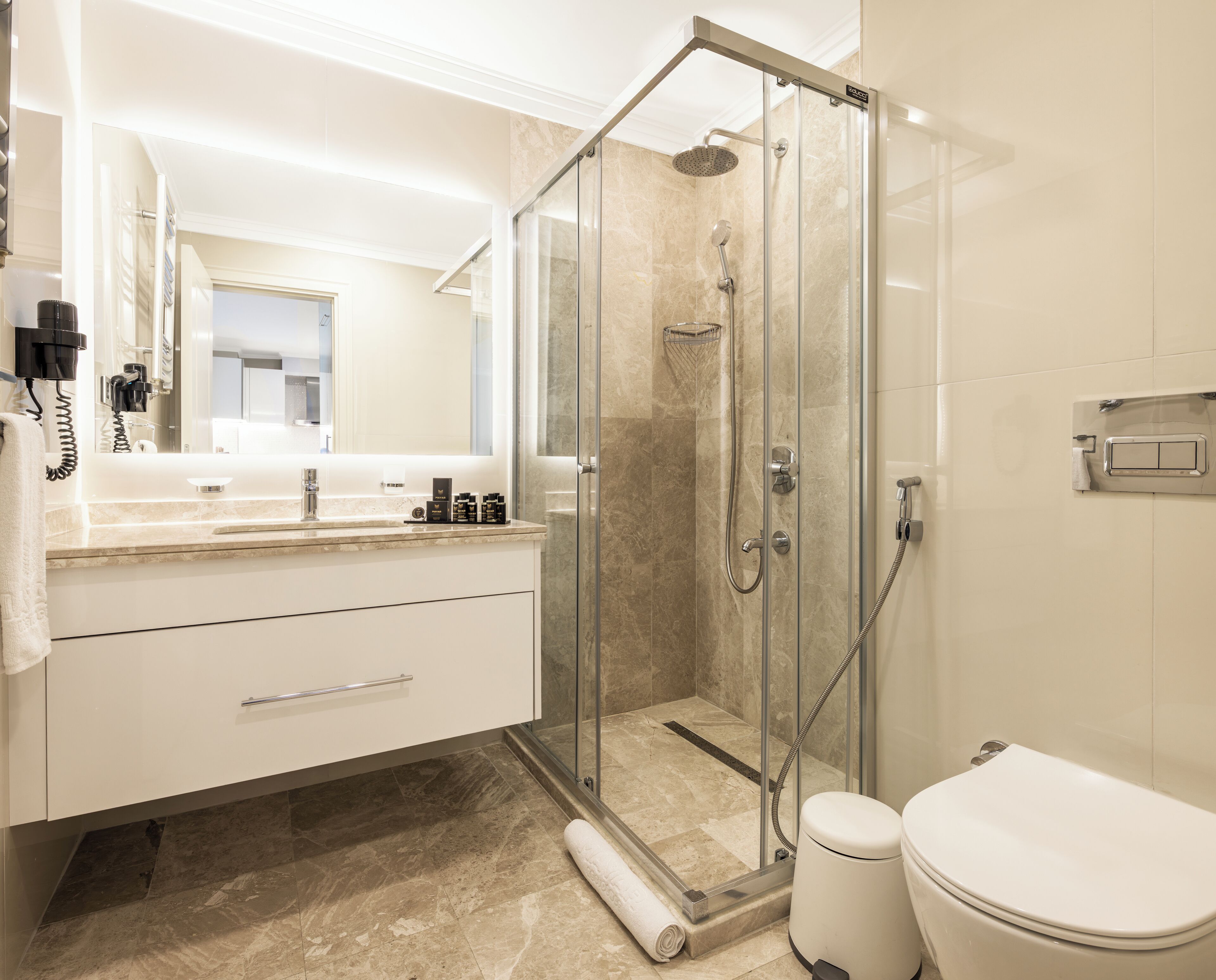 A modern bathroom with a glass-enclosed shower, a white toilet, and a vanity with a mirror and countertop.