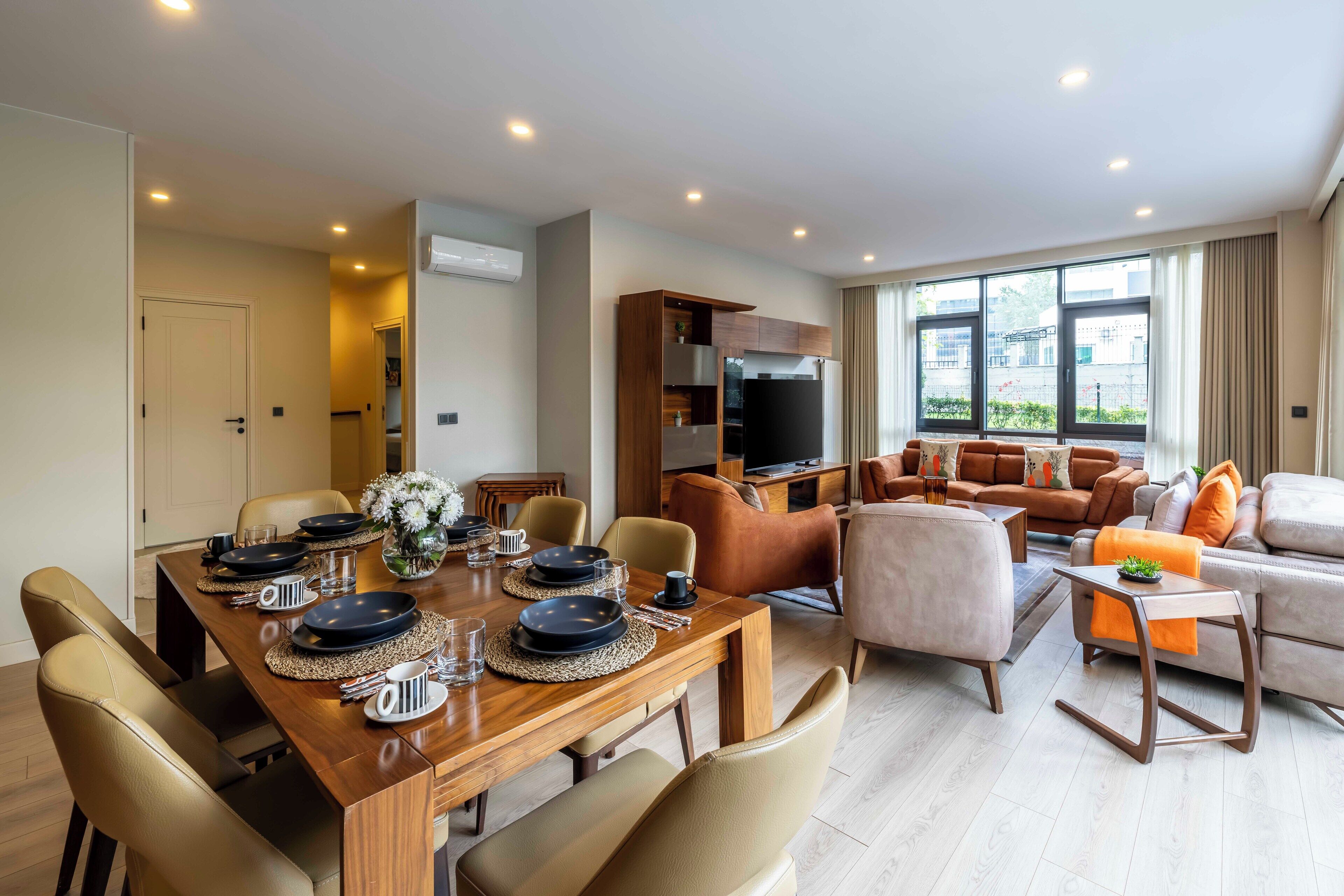Un salon moderne comprenant un ensemble de canapés, une table à manger pour quatre personnes et un coin cuisine avec un réfrigérateur et un four.