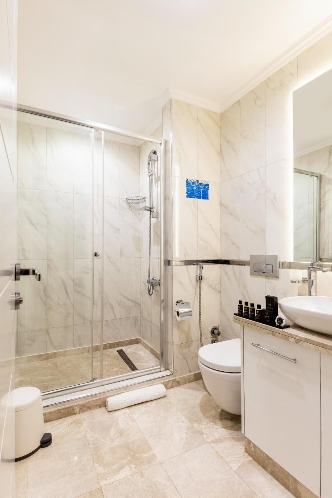 A modern bathroom with a glass-enclosed shower, a toilet, and a sink.