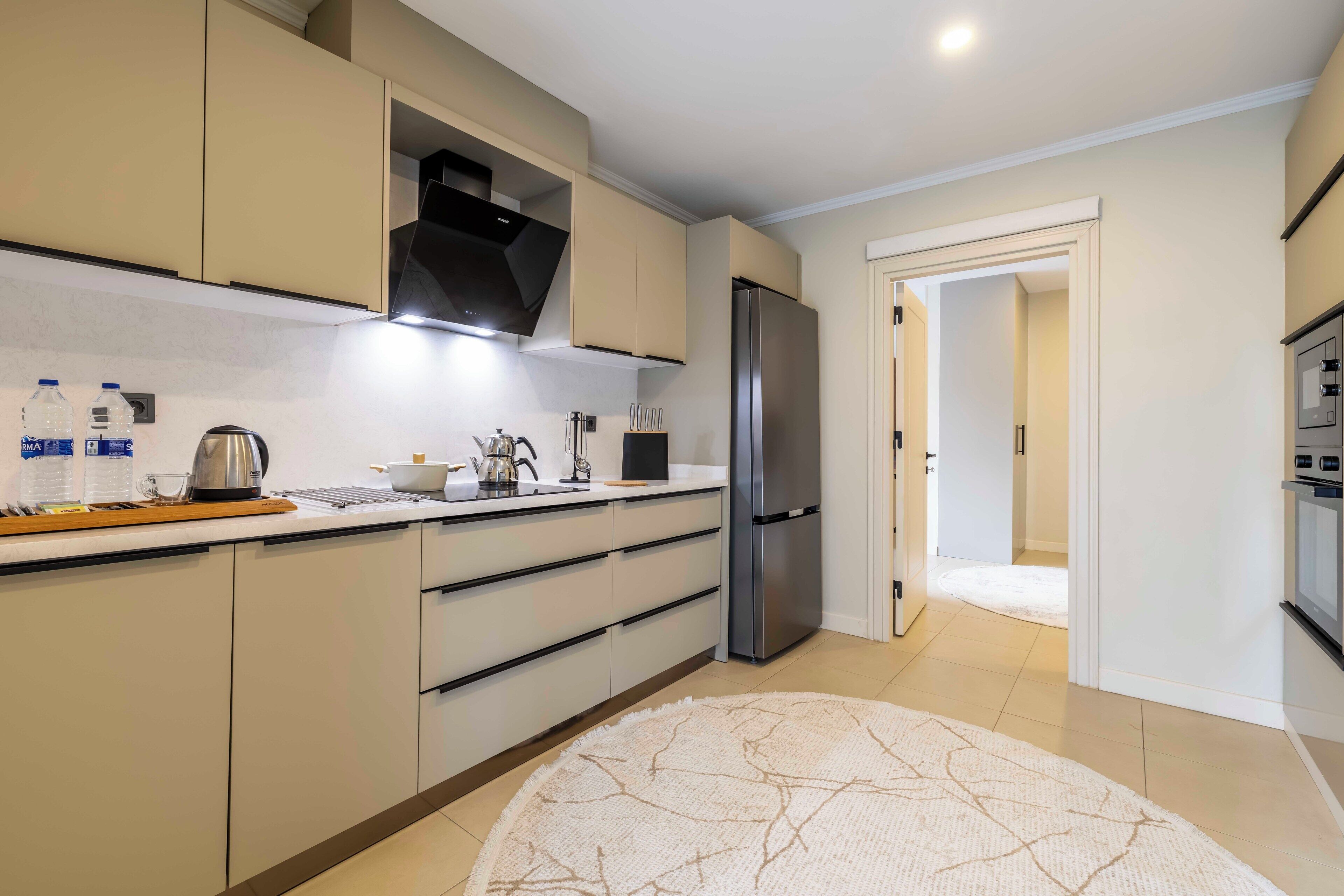 Una cocina moderna con un refrigerador de acero inoxidable, gabinetes blancos y una cafetera.