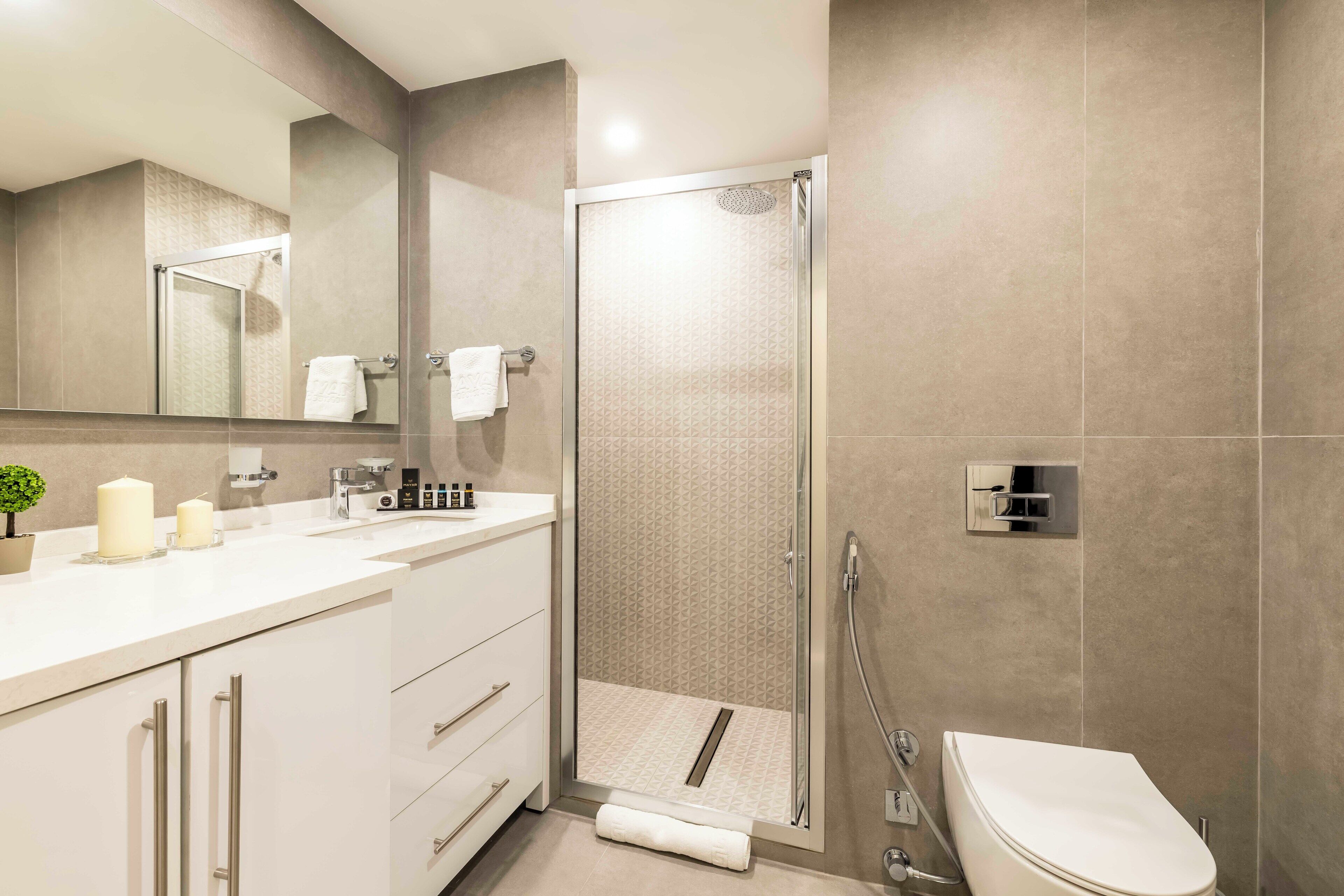 A modern bathroom with a glass-enclosed shower, a white sink, and a toilet.