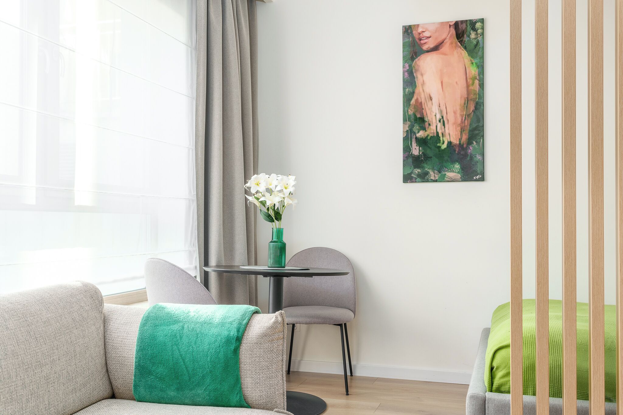 Un salon moderne avec un canapé, une petite table sur laquelle est posé un vase de fleurs et un tableau accroché au mur.