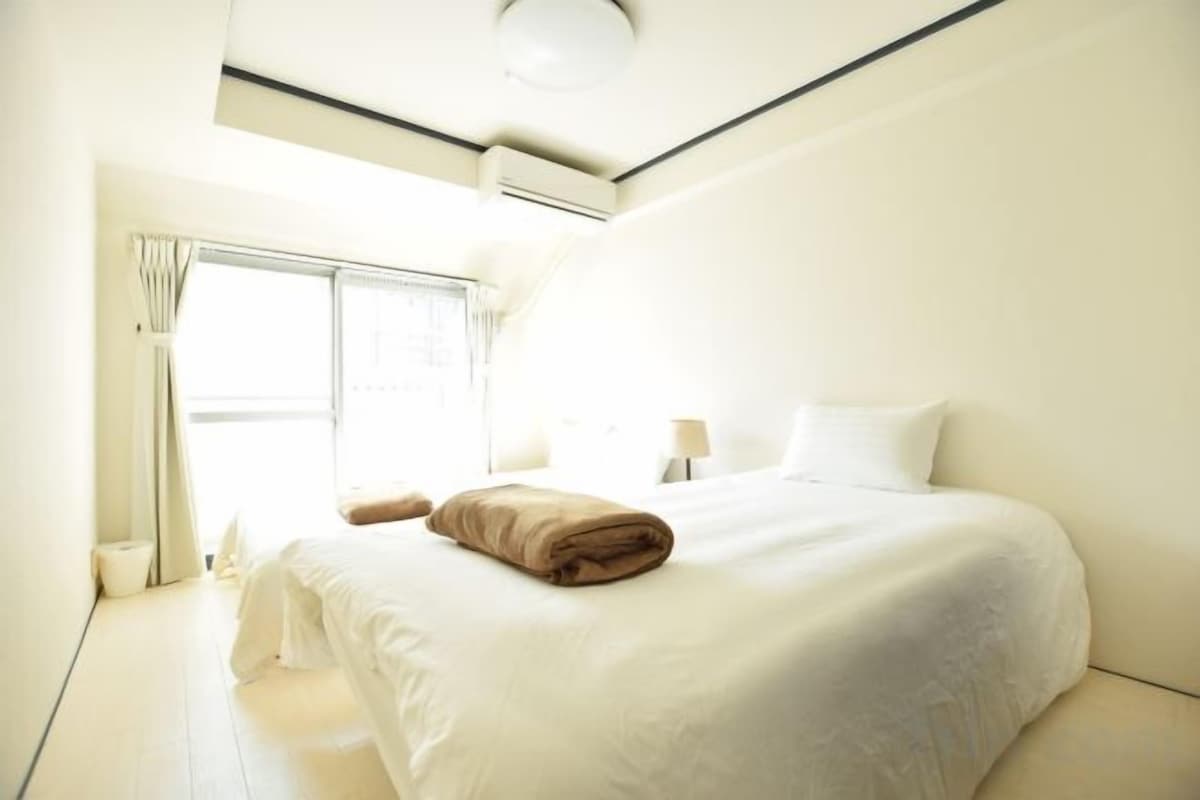 A hotel room with a bed, a window, and a ceiling light.