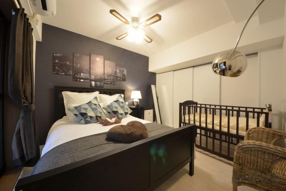 A bedroom with a bed, a nightstand, a lamp, a chair, and a wall-mounted mirror.