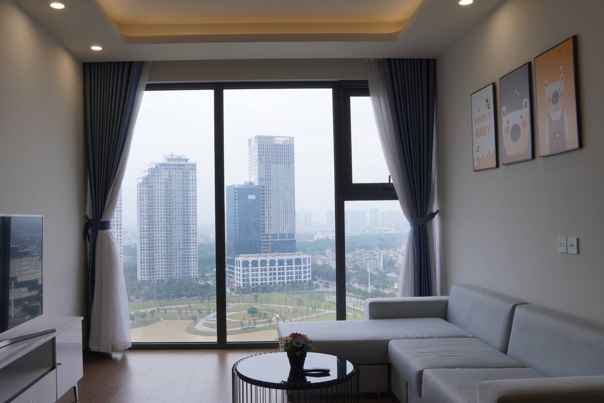 A modern living room with a large window, a sofa, a coffee table, and a flat-screen TV.
