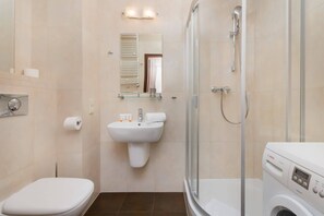 A modern bathroom with a toilet, sink, mirror, shower, and a Bosch washing machine.