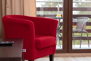 A red chair in a room with a glass door leading to an outdoor area.