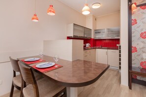 A compact kitchen with a dining area, equipped with modern appliances and pendant lighting.