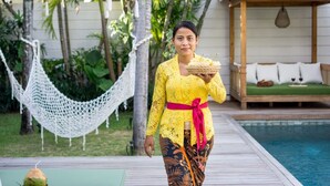 A person holding a woven basket, walking on a wooden deck with a pool and a hammock in the background. - Cozy 4BR Villa With Amazing Pool Area, Bali Villa 2210 (Seminyak)
