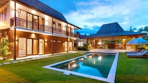 Ein zweistöckiges Haus mit Schwimmbad, Balkon und überdachter Sitzgelegenheit im Freien.