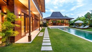 Ein modernes Haus mit Swimmingpool, überdachter Terrasse und gepflegtem Rasen.