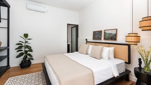 A bedroom with a bed, a potted plant, a bedside table, and a wall-mounted lamp. - Elegant 2BR Villa W/ Pool, Bali Villa 2221 (Canggu)