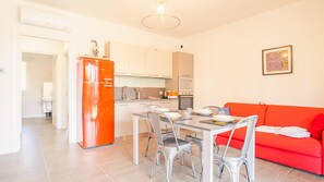 A compact living space with a dining area, kitchenette, and a red sofa.