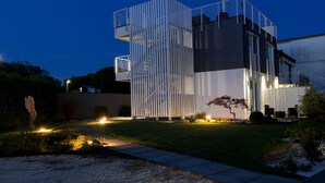 A modern building with a unique vertical design, outdoor seating, and well-lit pathways. - Le Nazioni B&B (Comacchio)