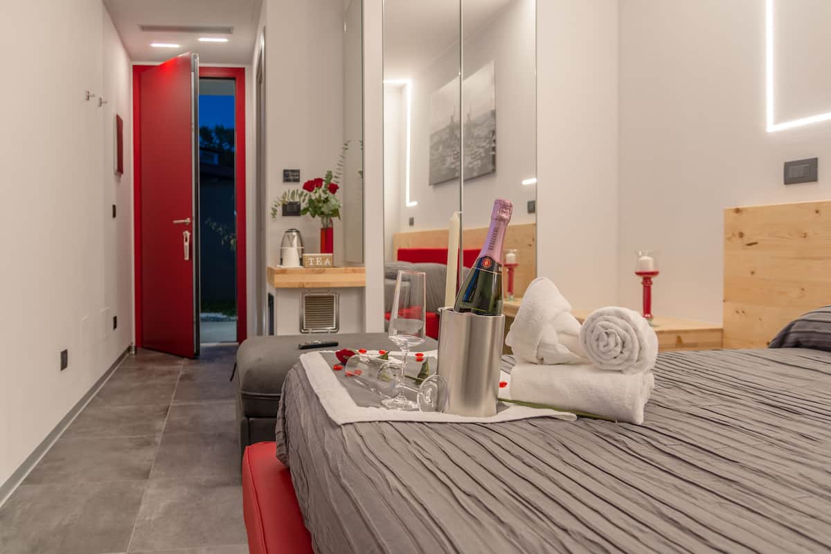 Quarto de hotel moderno com cama, mesa de cabeceira e espelho.