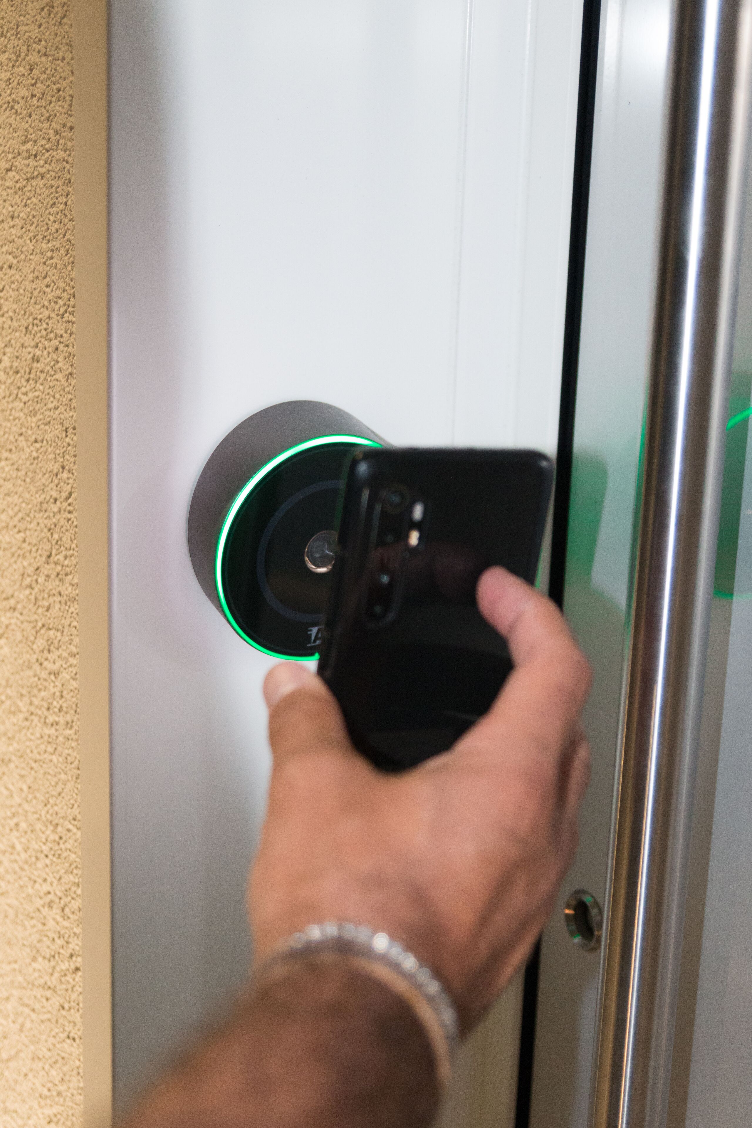 A hand using a smartphone to interact with a digital lock on a door.