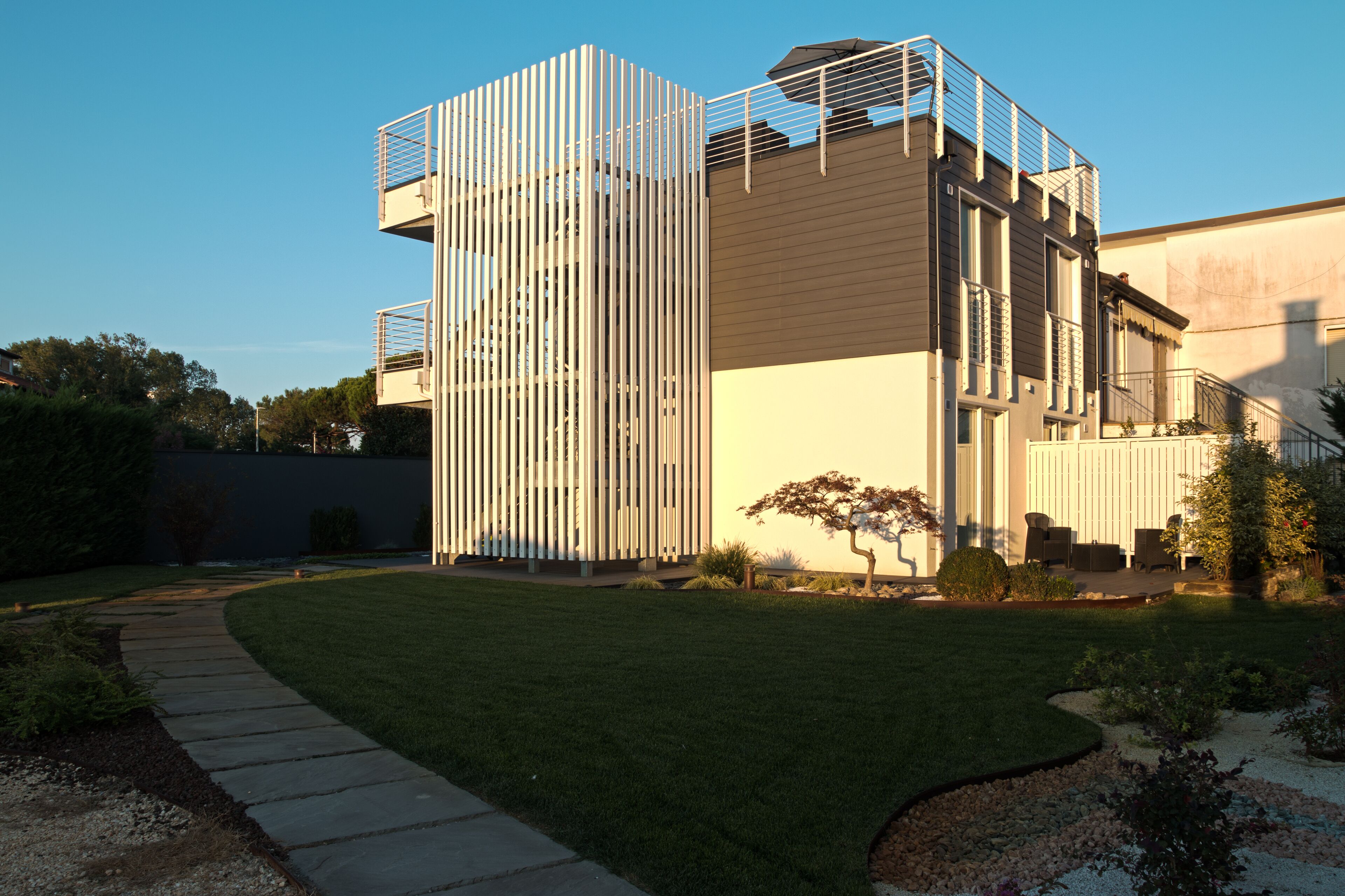 A modern building with a vertical garden facade, a paved pathway, and a well-maintained lawn.
