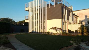 A modern building with a vertical garden facade, a paved pathway, and a well-maintained lawn.