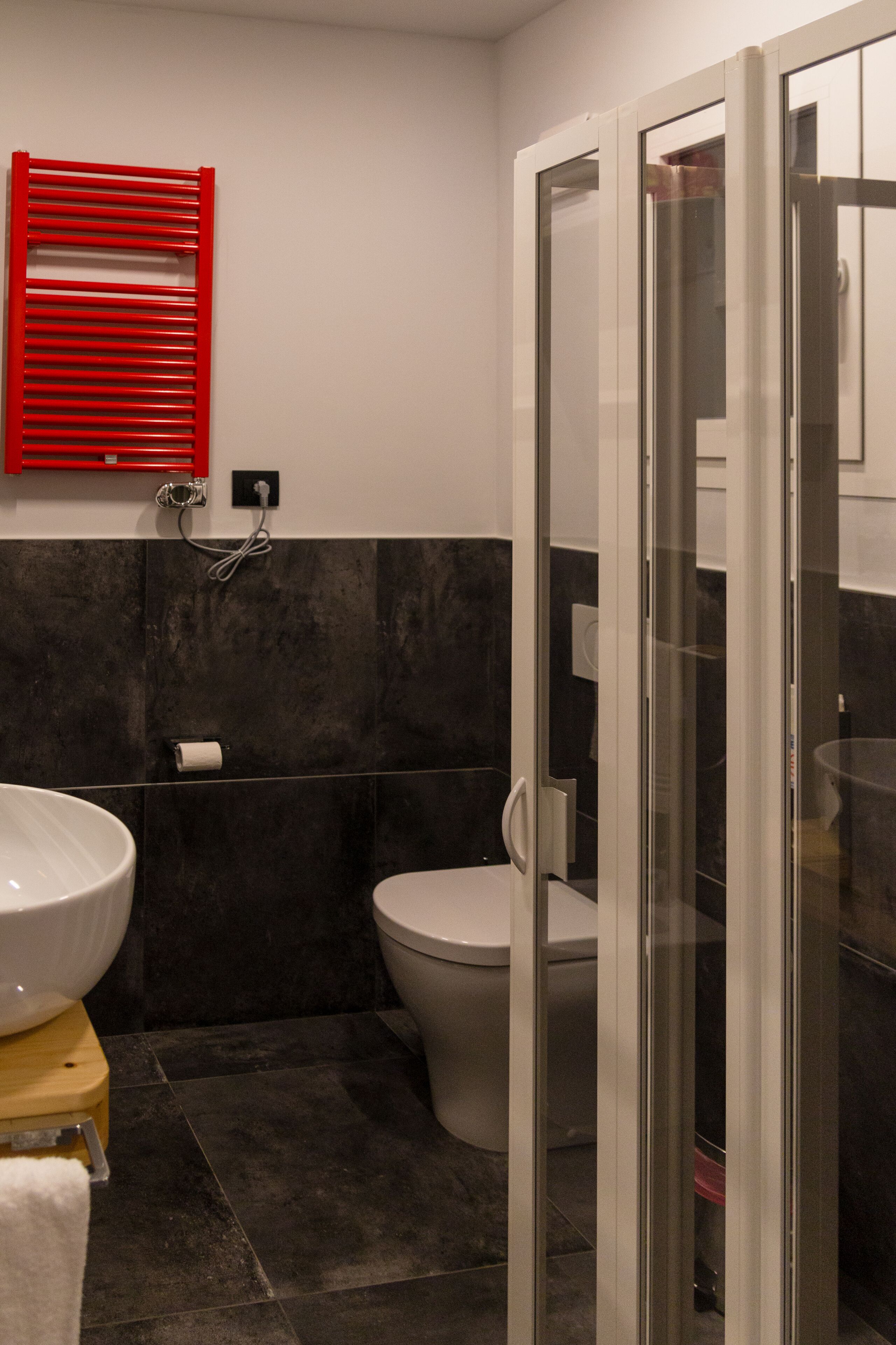 A modern bathroom with a glass shower enclosure, a white sink, and a toilet.