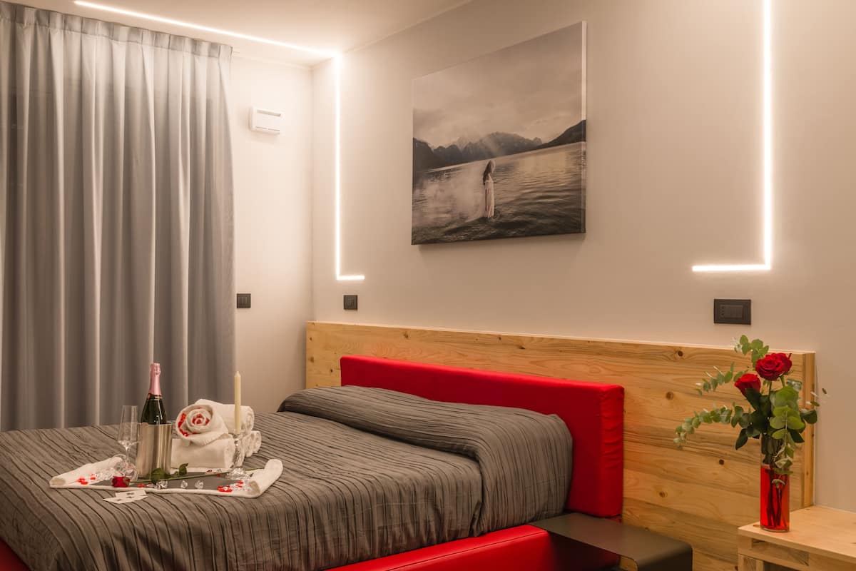 Quarto moderno com cama, mesa de cabeceira, quadro na parede e cortina.