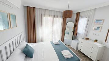 Quarto de hotel com cama, mesa de cabeceira, cômoda e espelho.