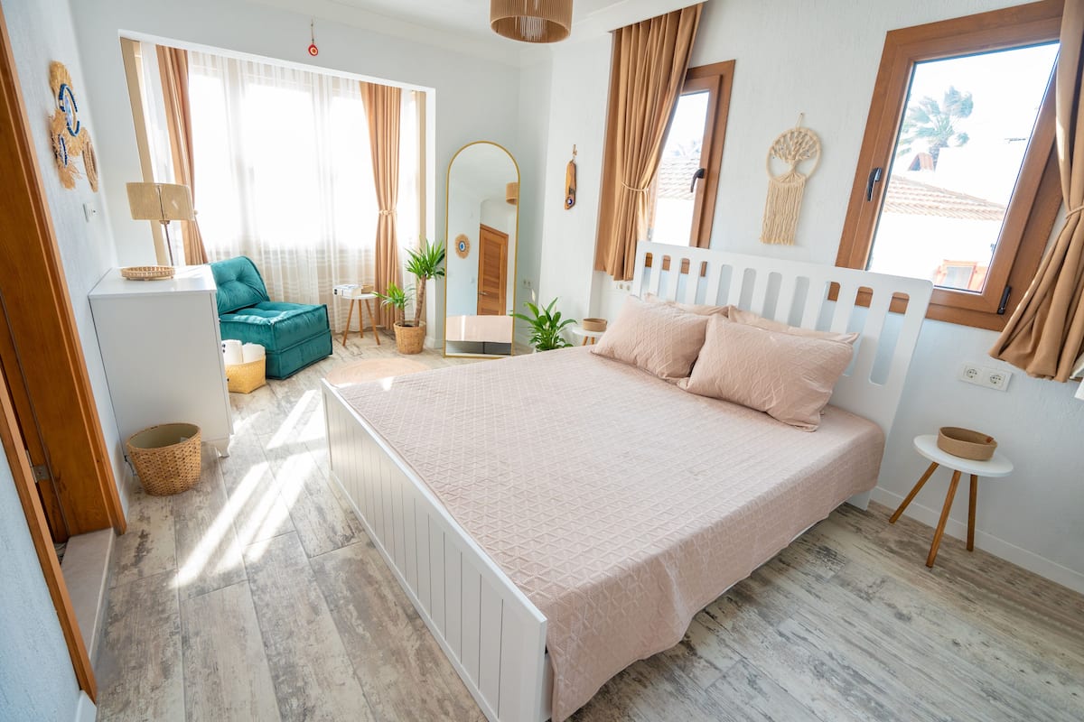 Une chambre à coucher avec un grand lit, une chaise, une petite table et un miroir.