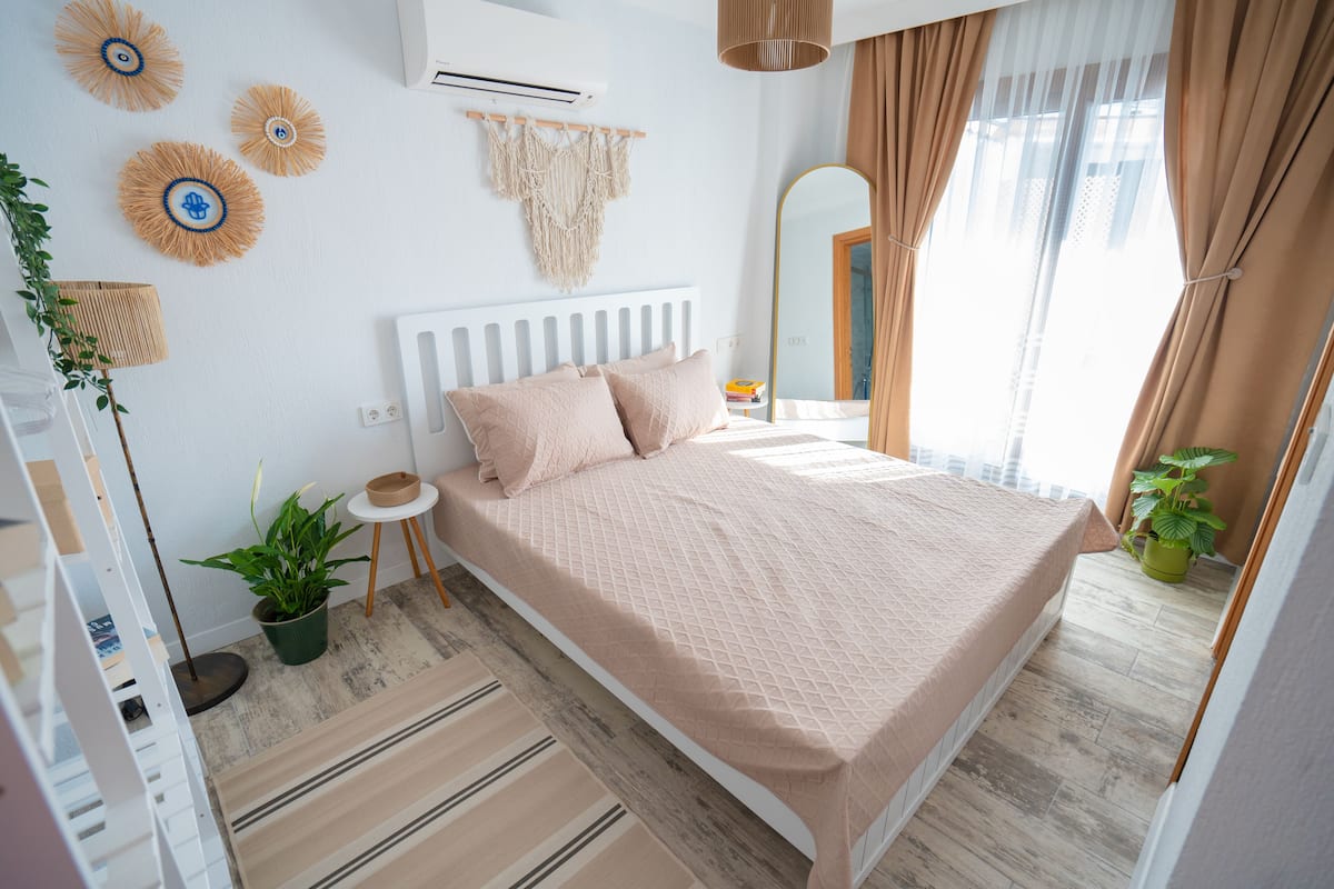 Une chambre à coucher avec un lit, une table de chevet, des plantes en pot et un grand miroir.