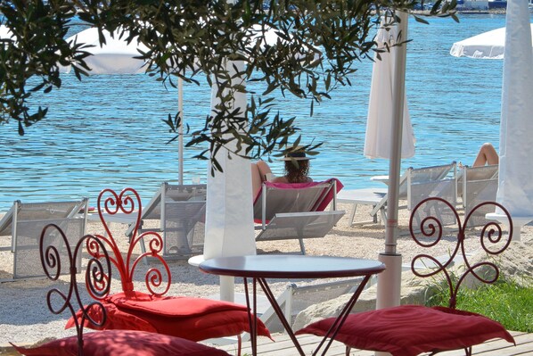 A beachside lounge area with outdoor seating and a view of the sea.