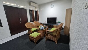 Ein Zimmer mit Korbmöbeln, einem Fernseher und einer Wanduhr.