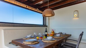 Une table à manger dressée avec des assiettes, des bols et des verres, une bouteille de vin et une carafe posées sur la table.
