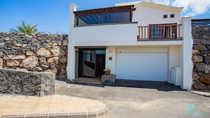 Une maison moderne à deux étages, dotée d’un mur en pierre, d’un garage et d’un balcon.
