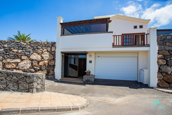 A modern two-story house with a stone wall, a garage, and a balcony. - A stunning new property to the holiday rental market (Playa Blanca)