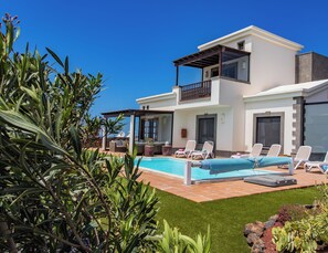 A modern two-story house with a swimming pool, outdoor seating, and lush landscaping. - A stunning new property to the holiday rental market (Playa Blanca)