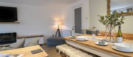 Una cucina moderna con un piano di lavoro in legno, una panca con cuscini, un tavolo da pranzo e un grande specchio.