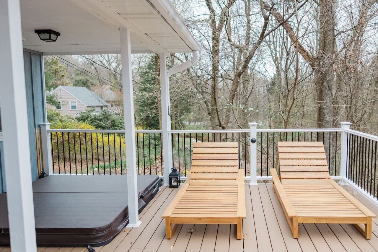 Une terrasse en bois avec deux chaises longues et un petit espace porche.
