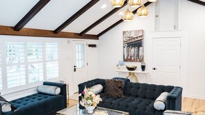 A living room with a dark blue sofa, a glass coffee table, and a decorative vase. - Superior Guest Room w Hot Tub w Outdoor view (New Hope)