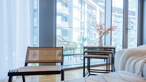 A modern living room with a wicker chair, a small wooden table with a vase, and a sofa with a cushion. - Aya - Stunning 1BR Surrounding The Sea Views & Ain Dubai (Dubai)