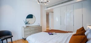 A modern bedroom with a bed, a dresser, a mirror, and a wardrobe. - Aya - Stunning 1BR Surrounding The Sea Views & Ain Dubai (Dubai)