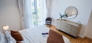 A bedroom with a bed, a dresser, a chair, and a large window. - Aya - Stunning 1BR Surrounding The Sea Views & Ain Dubai (Dubai)