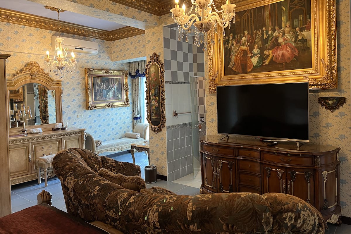 A luxurious room with ornate furniture, a large painting, and a chandelier.