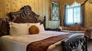 A classic, ornately decorated bedroom with a large bed, a sofa, and a painting on the wall.