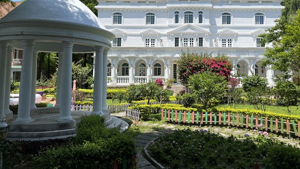 Un grand bâtiment blanc, de style classique, doté d’une façade symétrique, de nombreuses fenêtres et d’une entrée centrale.