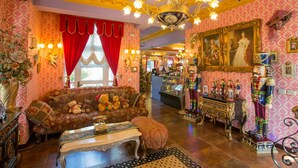Une pièce richement décorée, avec un canapé d’époque, un lustre somptueux et divers objets décoratifs.