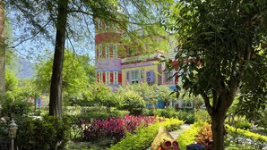 Un sentier de jardin avec, en arrière-plan, des bâtiments aux couleurs vives.