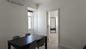 A modern, minimalistic room with a dark wooden table and four chairs, a large mirror, and a window providing natural light. - Beach Haven (Albufeira)