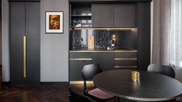 Une cuisine moderne avec des meubles de couleur sombre, un plan de travail en marbre et une table de salle à manger ronde, assortie de chaises.